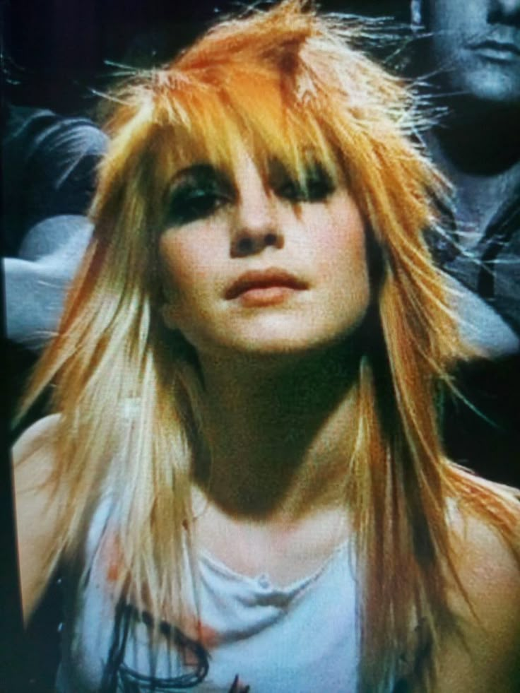 a woman with long blonde hair wearing a t - shirt and looking at the camera