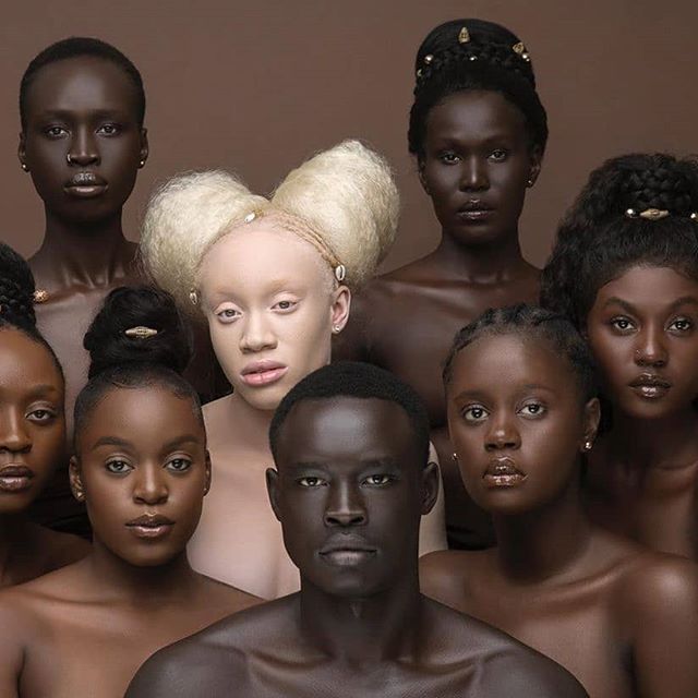 a group of naked black people with blonde hair and piercings on their heads, all looking at the camera