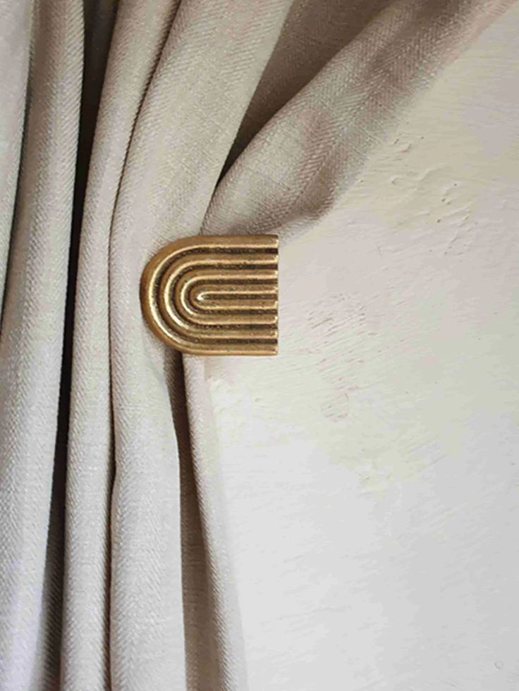 a gold brooch sitting on top of a white curtain