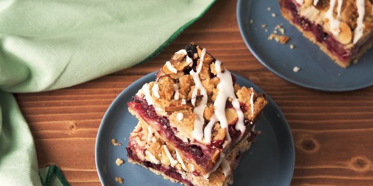 two blue plates topped with desserts on top of a wooden table next to green napkin