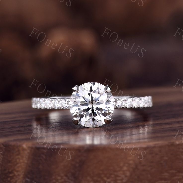 a diamond engagement ring sitting on top of a wooden table with diamonds around the band