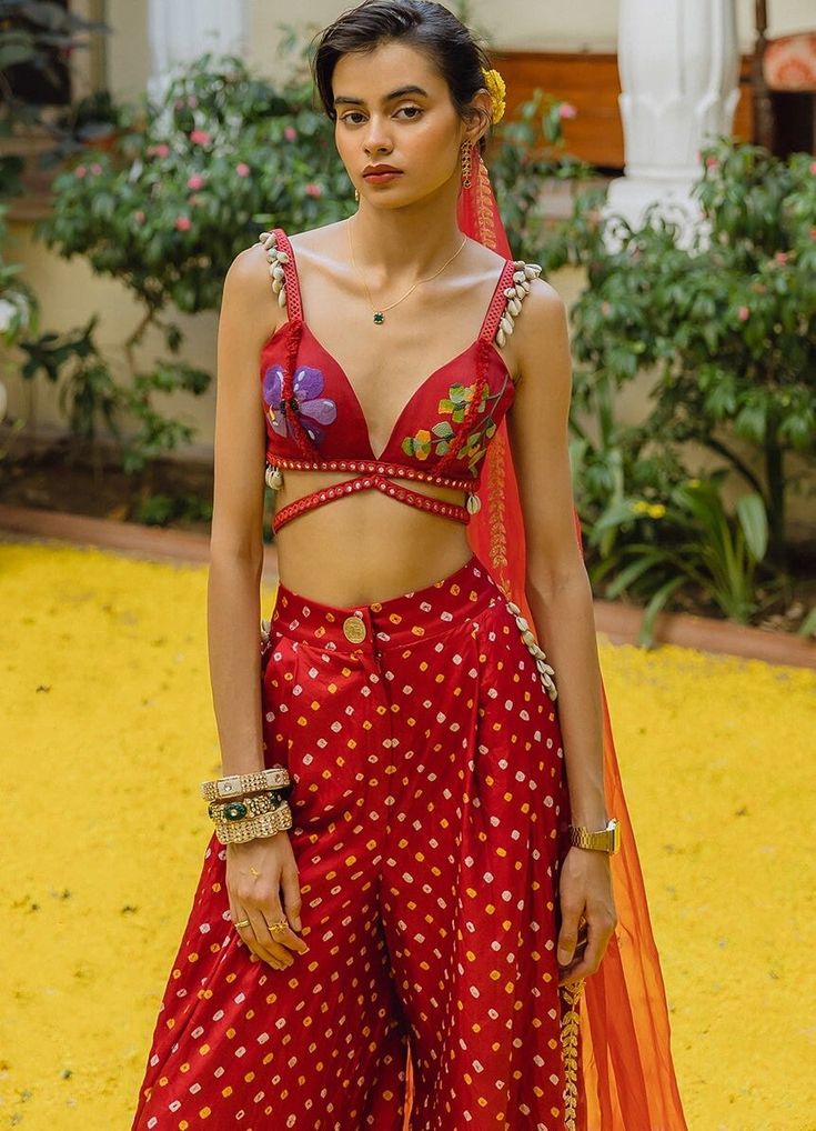 Featuring a handwoven red silk bralette featuring intricate embellishments, beads, shell and mirrorwork. Teamed with vintage-inspired red Bandhani silk trousers and a red organza dupatta with a beaten gold zardosi border. Composition : Bralette - Handwoven Silk, Pants - Bandhani Silk trousers, Dupatta - Organza Care: Dry Clean Only and Vacuum Storage This product can be customized for sleeves, length of blouse and neckline Delivery : 6-8 weeks as the product is hand crafted. Check Size Guide or choose MySize for free customisation (All Sizes above XL can be made at 15% additional cost) For more information and sizes please contact fabiliciousfashion@gmail.com or visit our Copenhagen studio.About the Designer : The Little Black Bow collection is an absolute delight for fashion enthusiasts w Zardosi Border, Silk Bralette, Vacuum Storage, Silk Trousers, Organza Dupatta, Silk Yarn, Silk Pants, Tiny Flowers, Red Silk