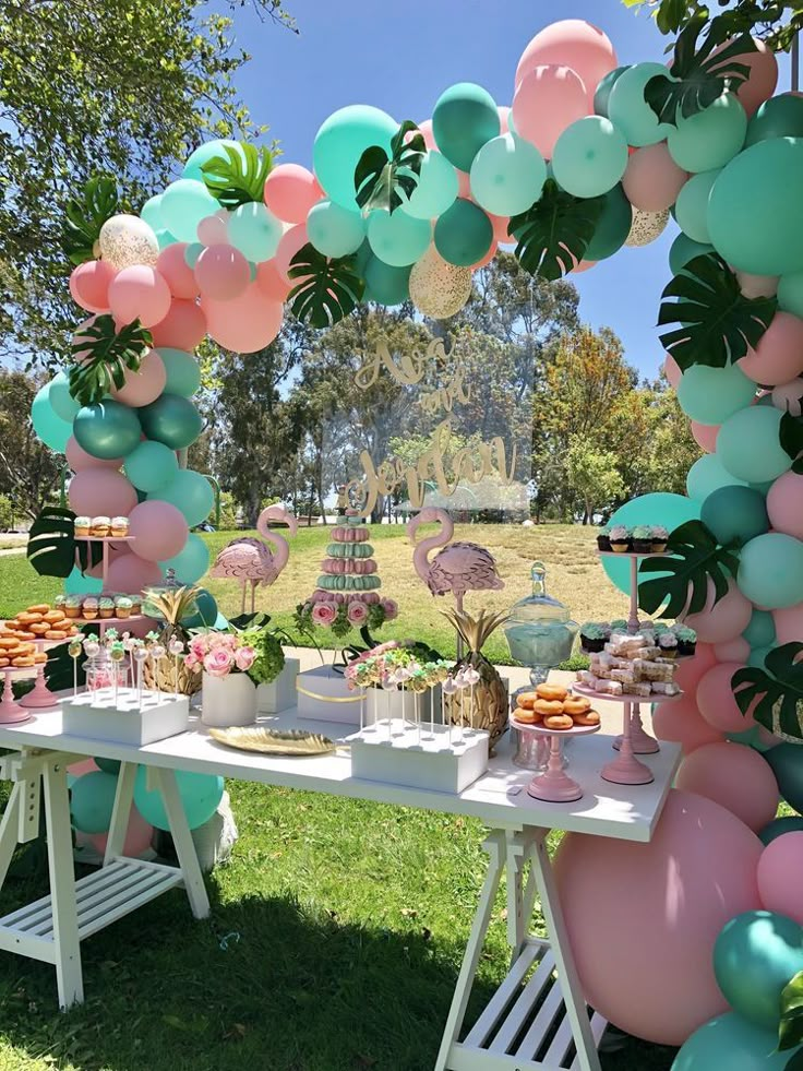 an outdoor party with balloons and desserts