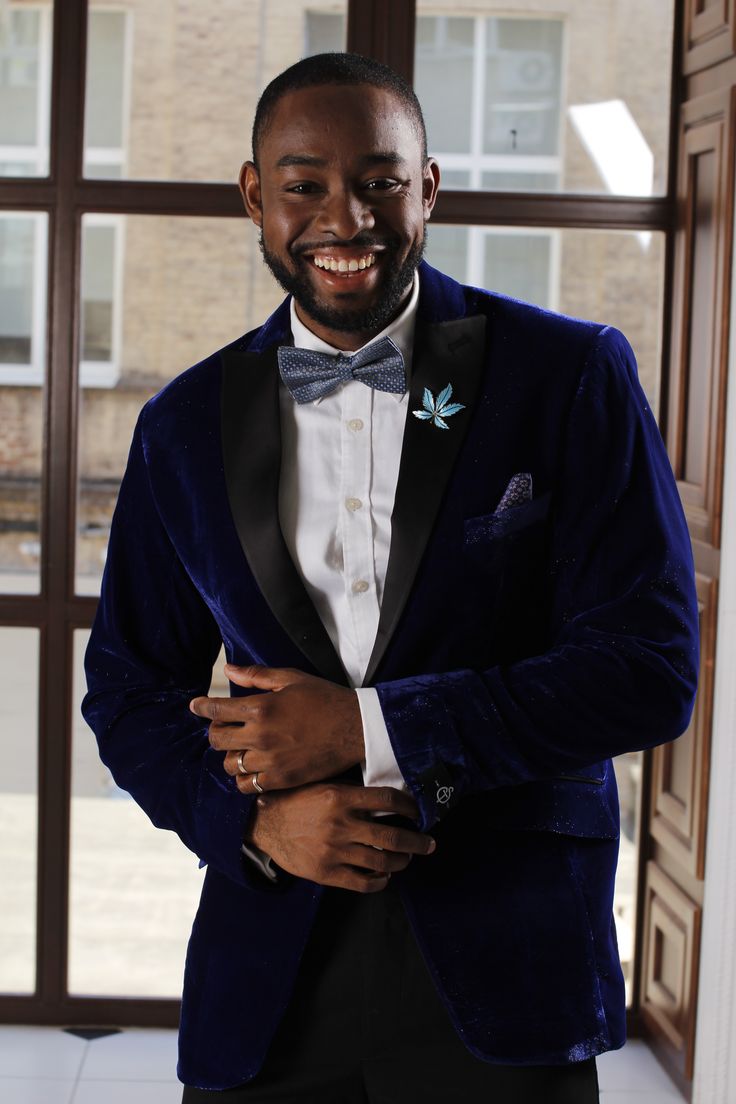 a man in a tuxedo is smiling and posing for the camera with his hands on his chest