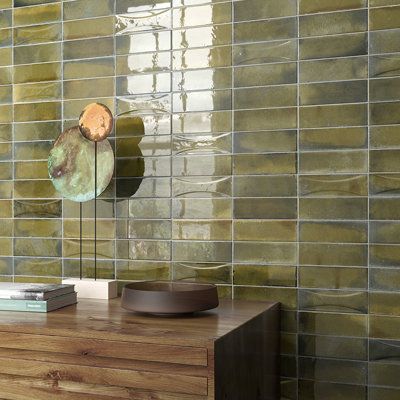 a wooden table sitting next to a green tiled wall