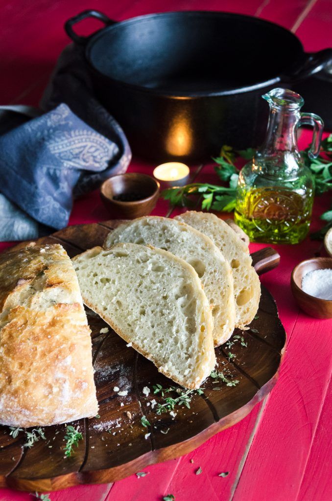 some bread is on a wooden plate with other food items around it and an oil bottle in the background