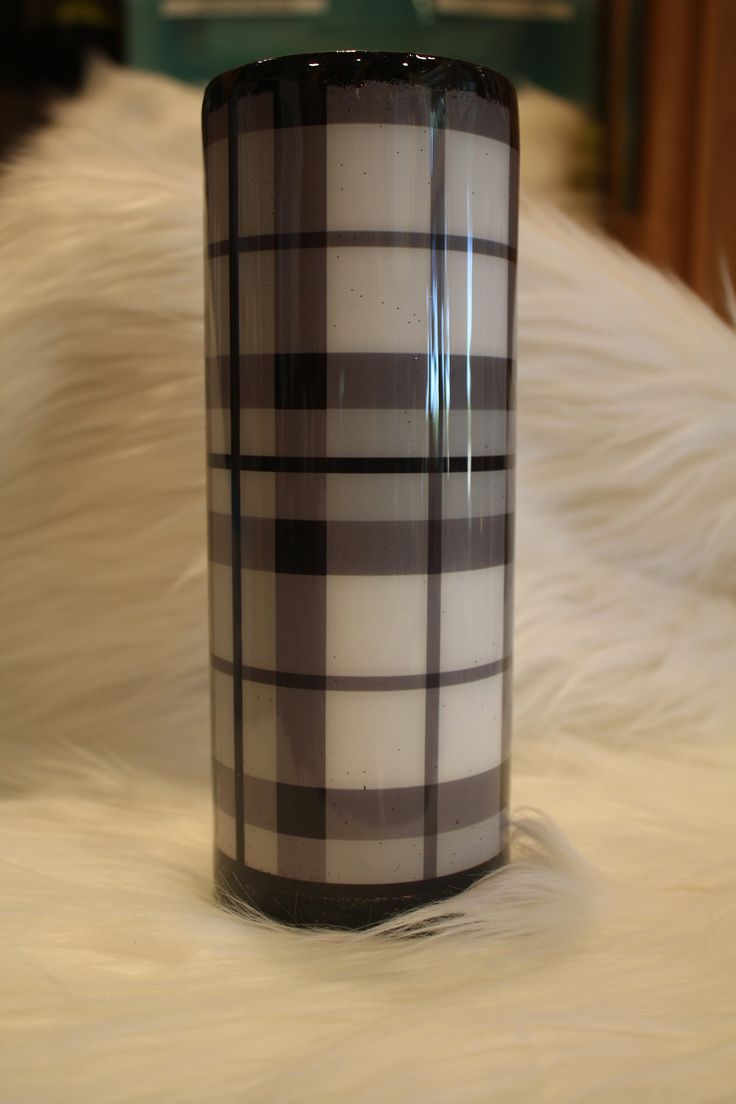 a black and white coffee cup sitting on top of a fur covered floor next to a window