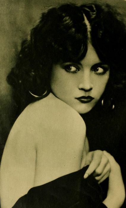 an old black and white photo of a woman with dark hair wearing a strapless dress