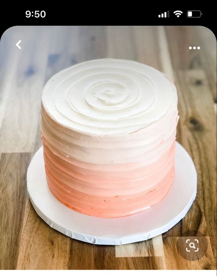 a white and pink cake sitting on top of a wooden table