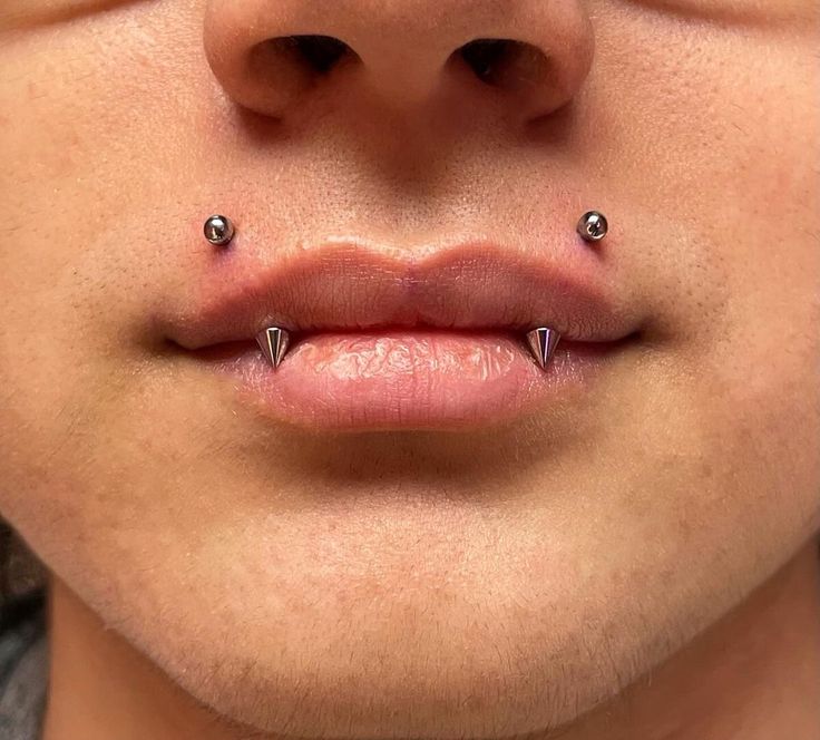 a close up of a person's nose with piercings on their lips and tongue