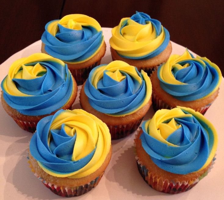 cupcakes with blue and yellow frosting on a white plate