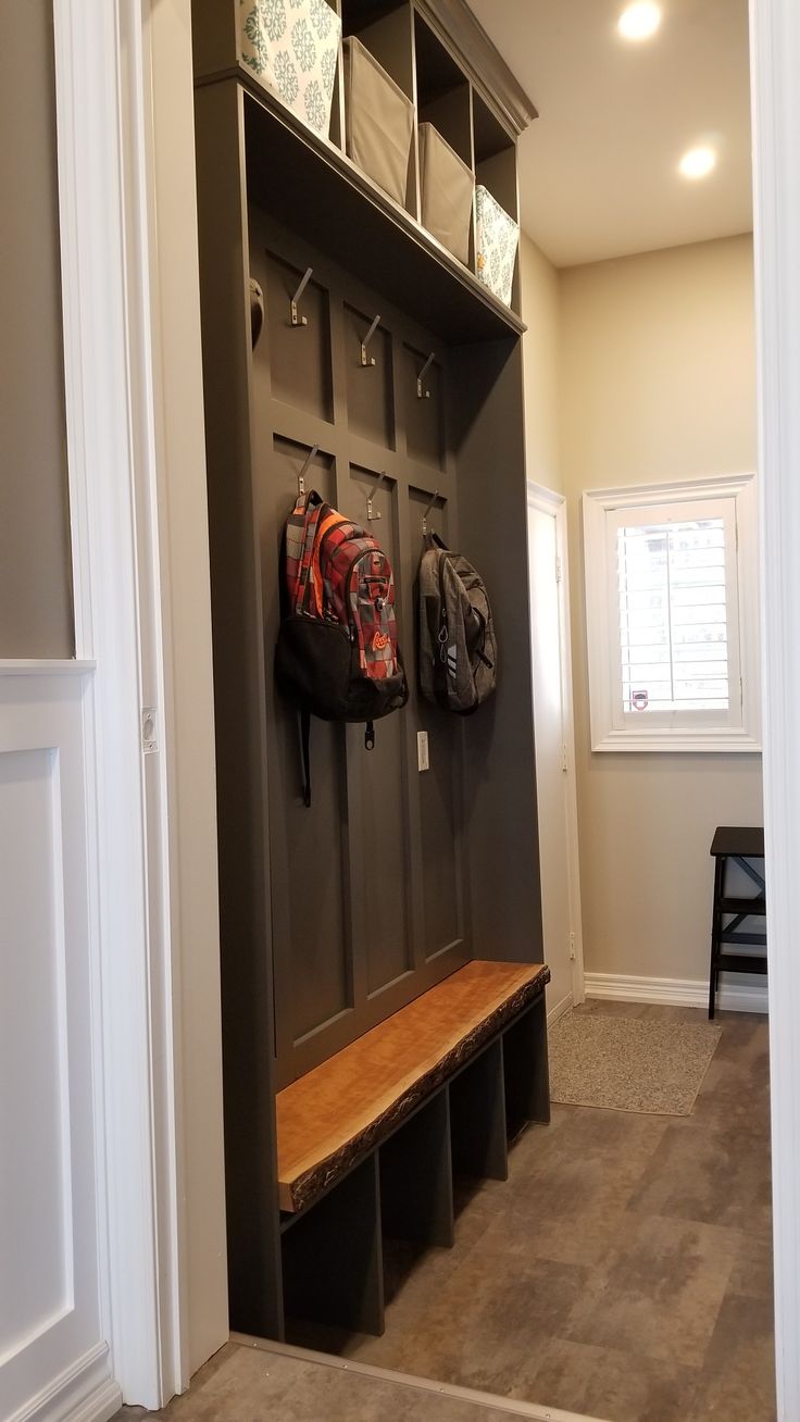 an entryway with a bench and coat rack filled with backpacks on it's sides