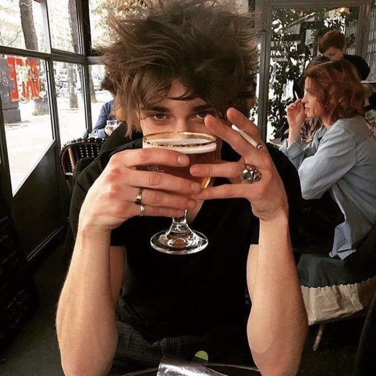 a woman sitting at a table with a wine glass in front of her face and looking into the camera