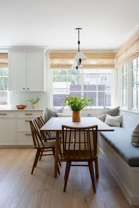 a kitchen filled with lots of white furniture next to a wooden dining room table and chairs