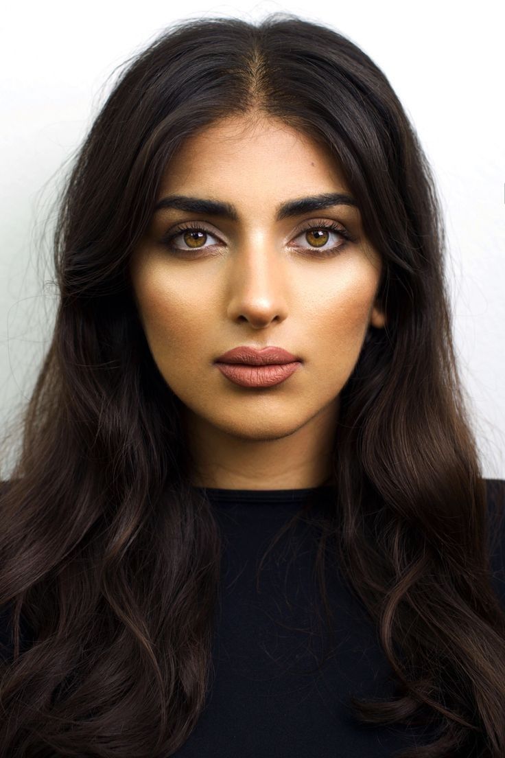 a woman with long dark hair and makeup looks at the camera while posing for a photo