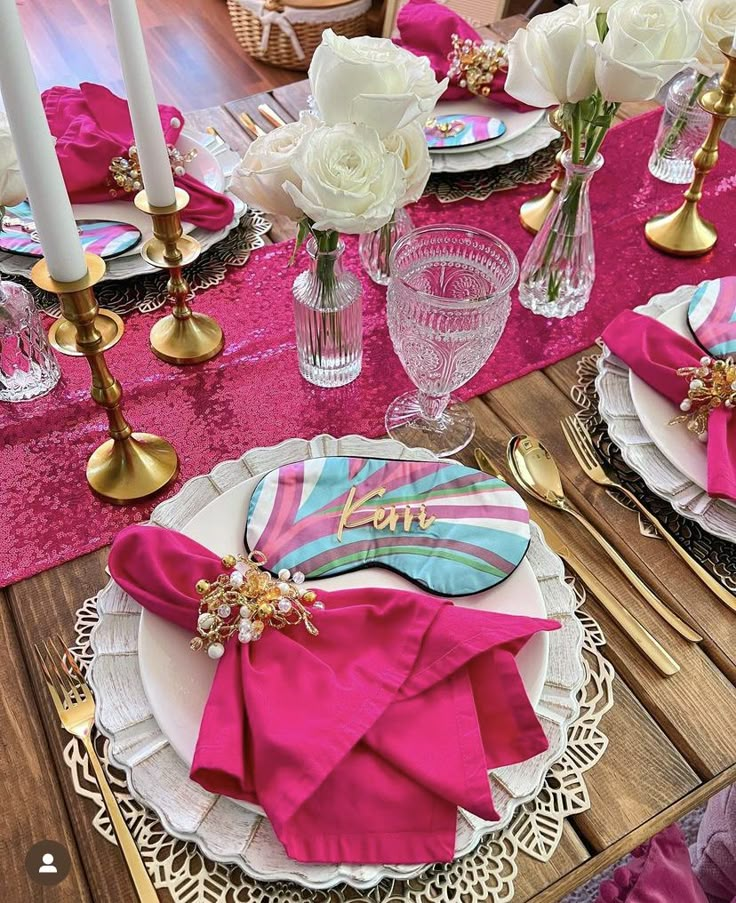 the table is set with pink napkins and gold place settings