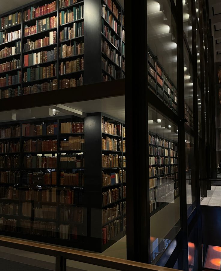 a library filled with lots of books on top of shelves next to a stairwell leading up to the second floor