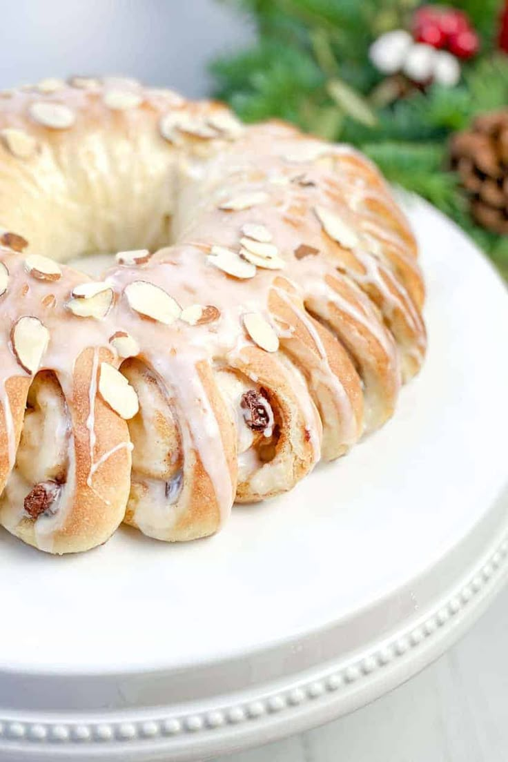 a white plate topped with a bundt cake covered in frosting and almonds