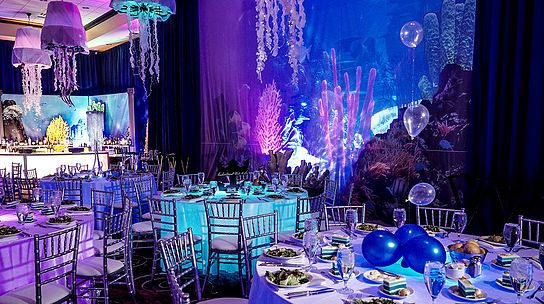 a room filled with tables and chairs covered in purple lights