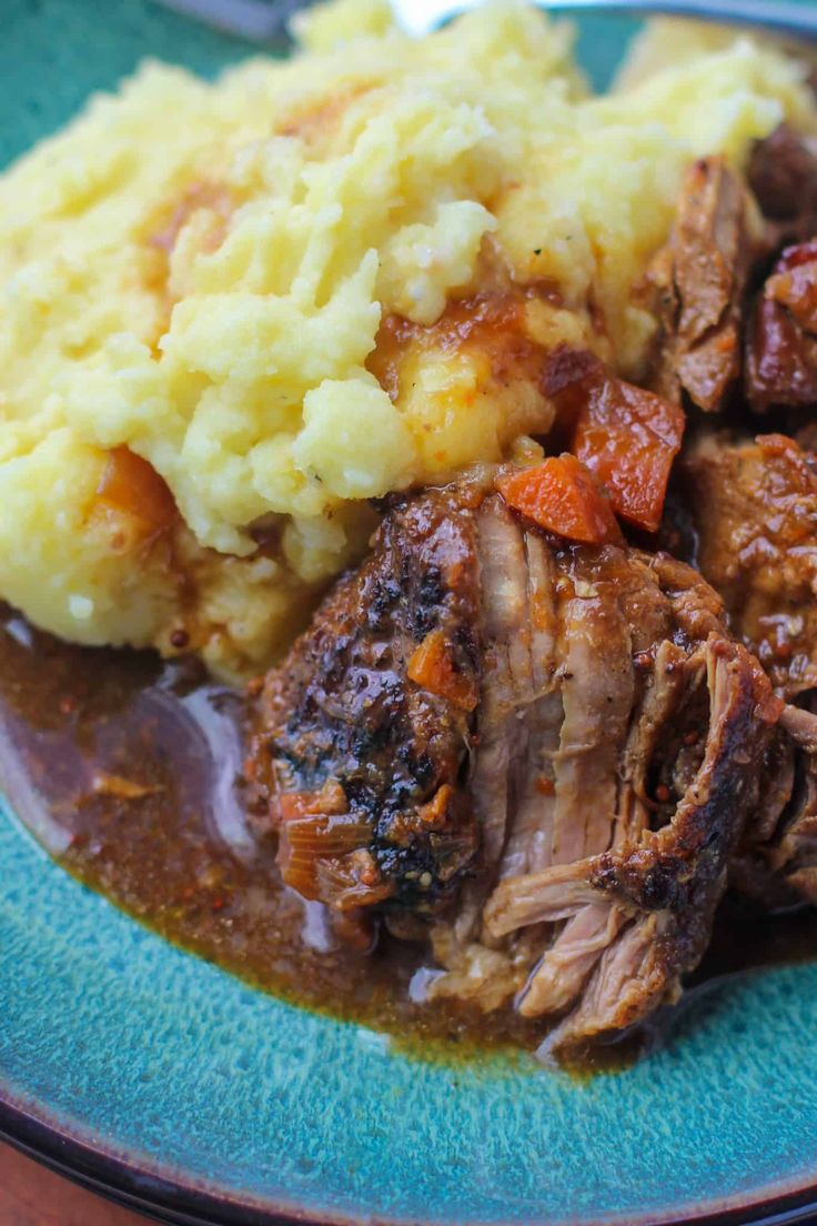 a blue plate topped with meat and mashed potatoes