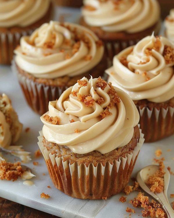 several cupcakes with white frosting and sprinkles on a tray