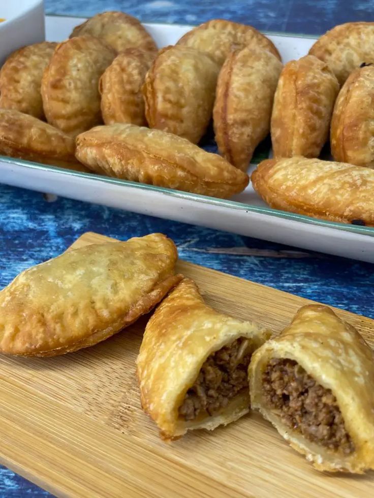 some pastries are sitting on a cutting board next to another tray with other pastries