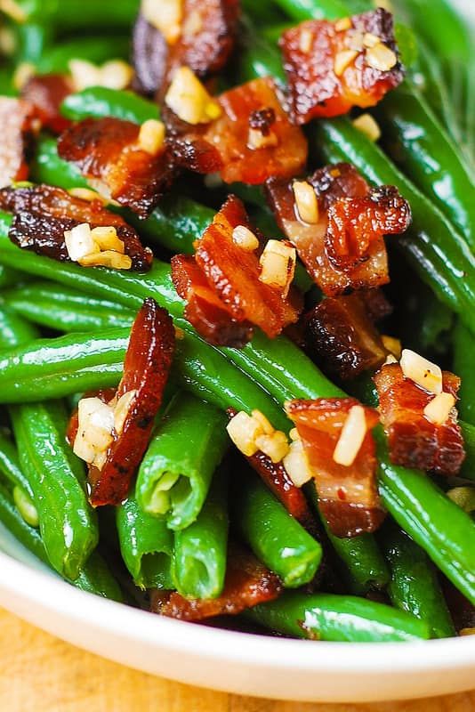 a white bowl filled with green beans and bacon