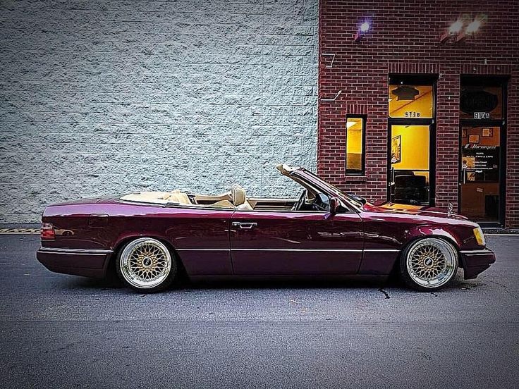 a purple convertible car parked in front of a brick building with its open top down