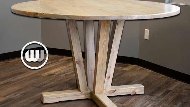 a round wooden table sitting on top of a hard wood floor next to a wall