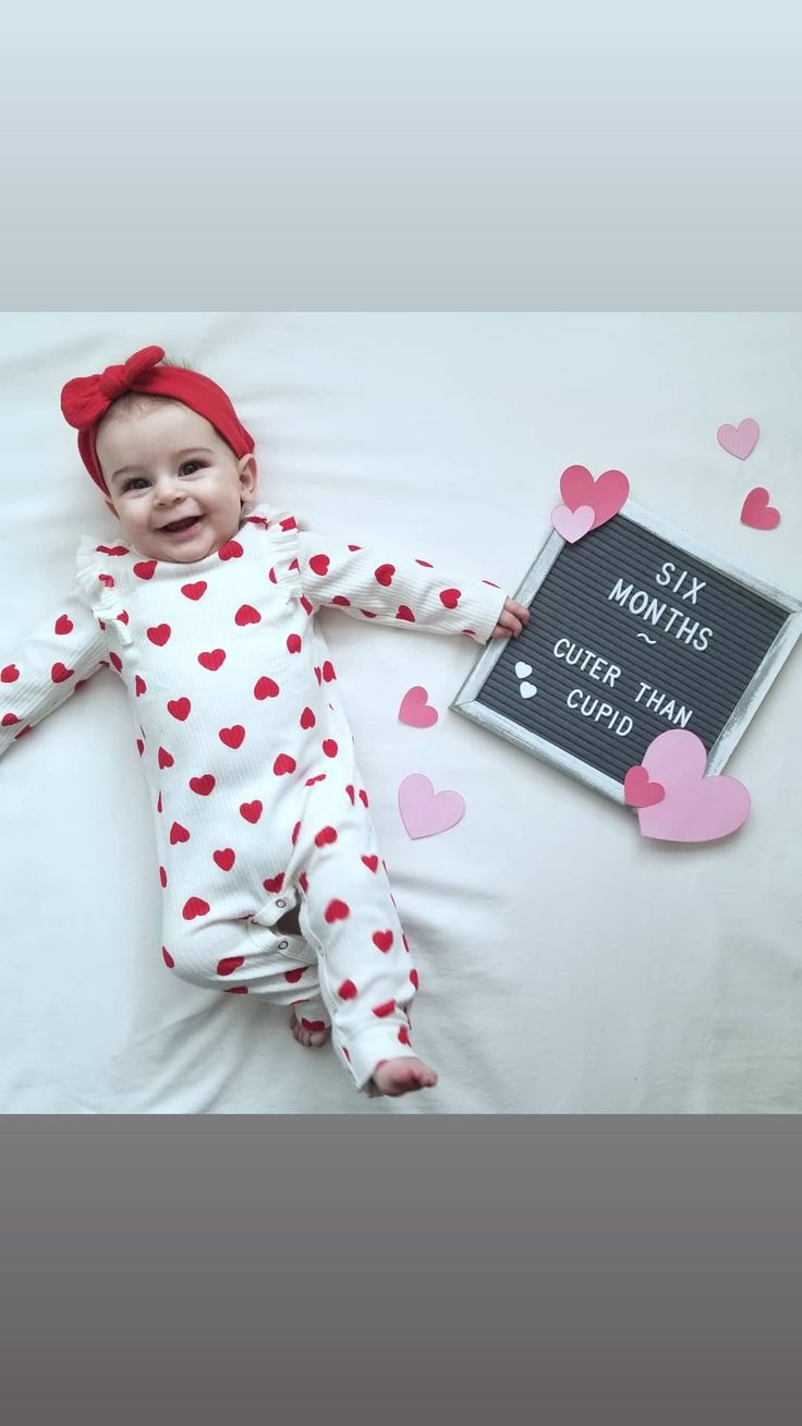 a baby laying on top of a bed next to a sign