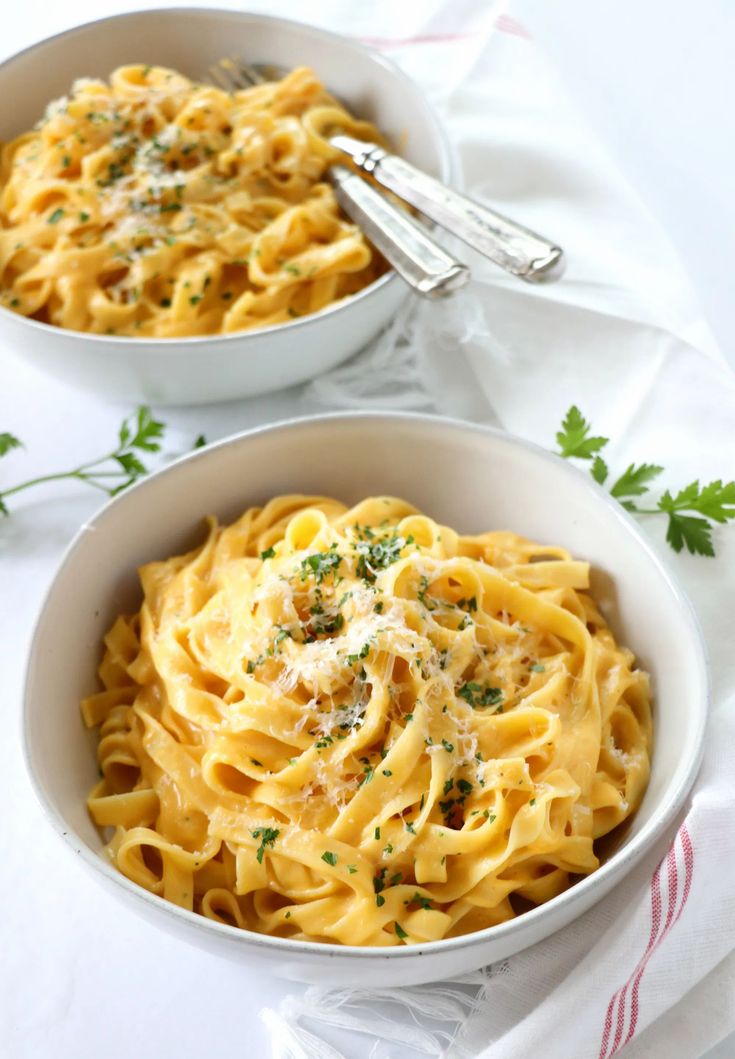 two bowls filled with pasta and garnished with parsley