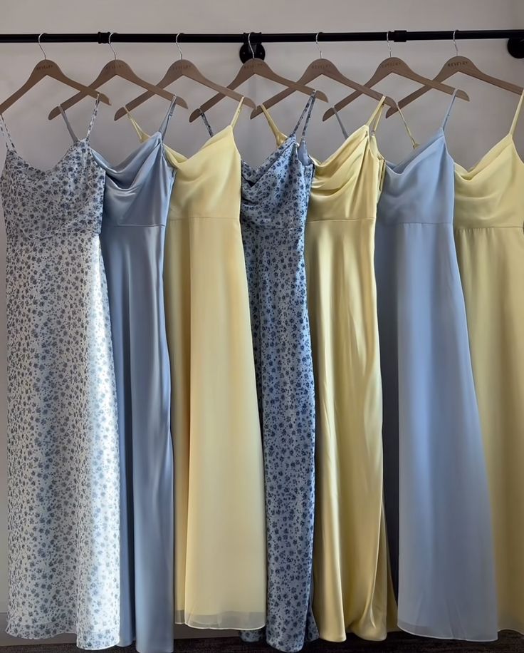 four dresses hanging on a rack in front of a wall