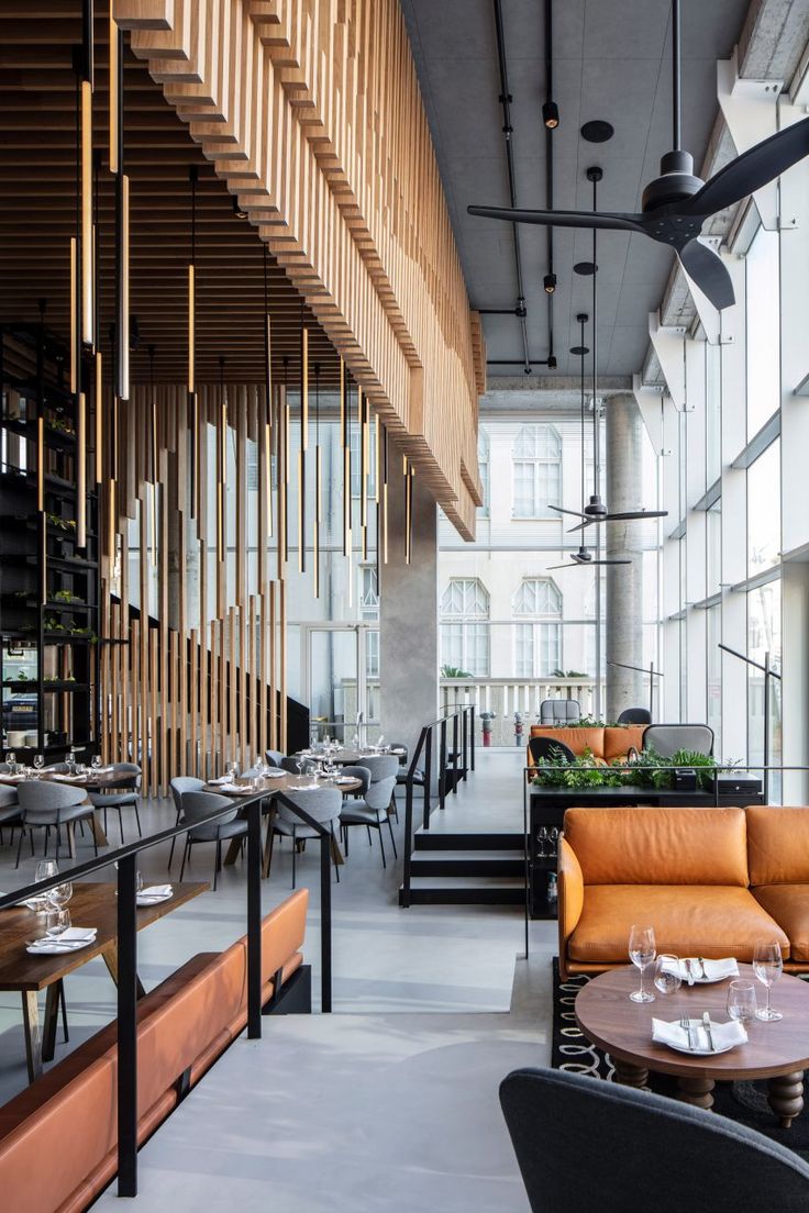 the interior of a restaurant with tables, chairs and couches in front of large windows