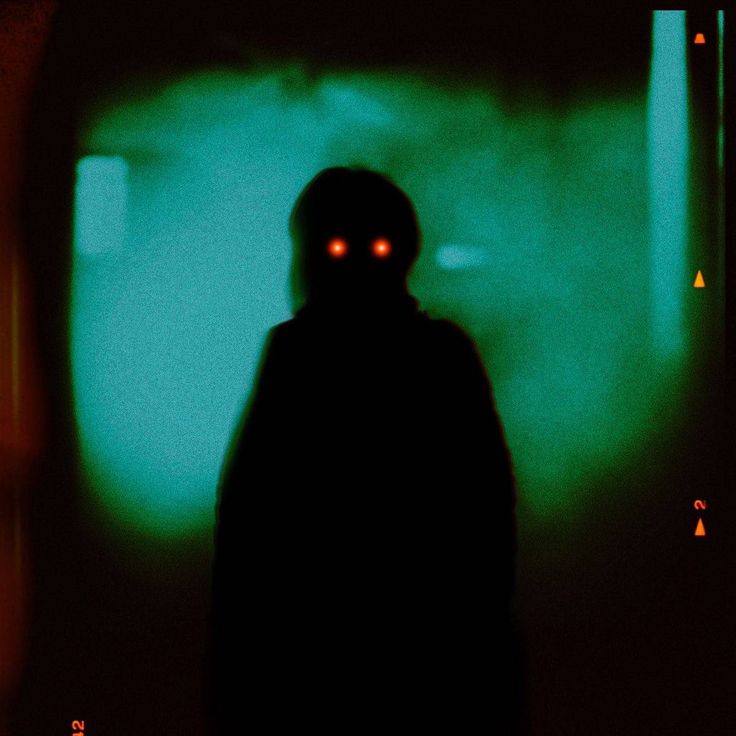 a person standing in the dark with red eyes and a black hoodie over their head