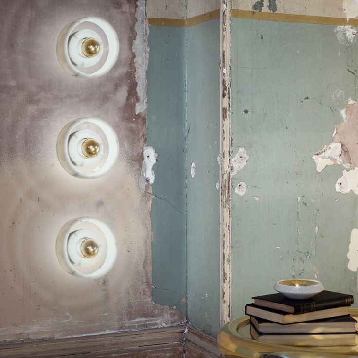 a room with peeling paint and some lights on the wall next to a stack of books