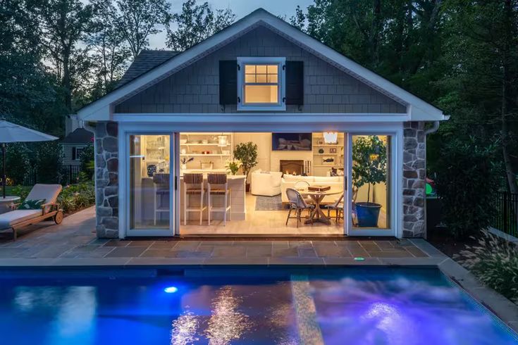 a backyard with a pool, patio and outdoor living area at night in the evening