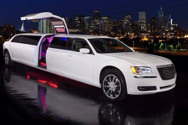 a white limo parked in front of a city at night