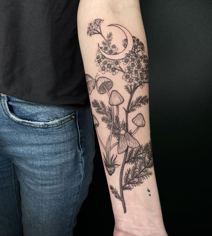 a woman with a tattoo on her arm holding onto a flower and mushroom plant that is growing out of the ground