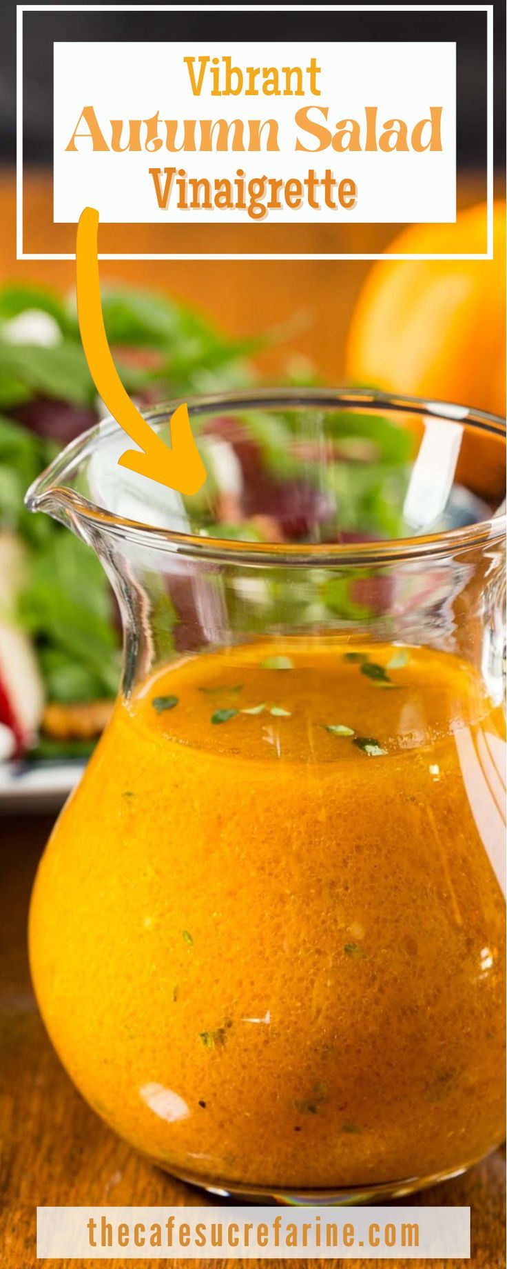 an orange liquid in a glass pitcher on top of a wooden table next to vegetables