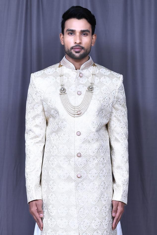 Light beige jacquard sherwani with floral and thread embroidery. Comes with white banglori silk churidar and anarkali kurta.
Components: 3
Pattern: Embroidered
Type Of Work: Floral, Thread
Neckline: Mandarin collar
Sleeve Type: Full
Fabric: Banglori silk, Sherwani: Jacquard
Color: Beige
Other Details: 
Closure: Sherwani - Front buttons
Note: Mala worn by the model is not for sale.
Occasion: Wedding,Groom - Aza Fashions Formal Beige Sherwani With Chikankari Embroidery, Cream Bandhgala With Cutdana For Eid, Cream Jamawar Sherwani For Wedding, White Jamawar Bandhgala For Eid, White Jamawar Bandhgala For Wedding, Ceremonial Cream Bandhgala With Chikankari Embroidery, Off White Bandhgala With Naqshi For Festive Occasions, Off White Naqshi Bandhgala For Festive Occasions, White Jamawar Bandhgala For Diwali