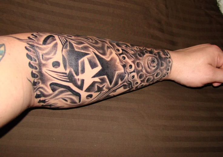 a man's arm with tattoos on it and his hand holding something in the air