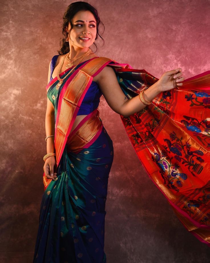 a woman in a blue and red sari with her hands on her hips, posing for the camera