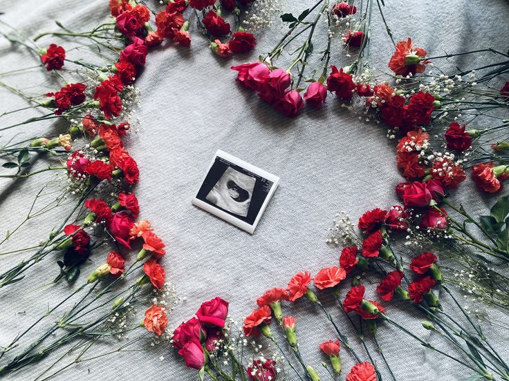 flowers arranged in the shape of a heart on top of a table with a photo frame