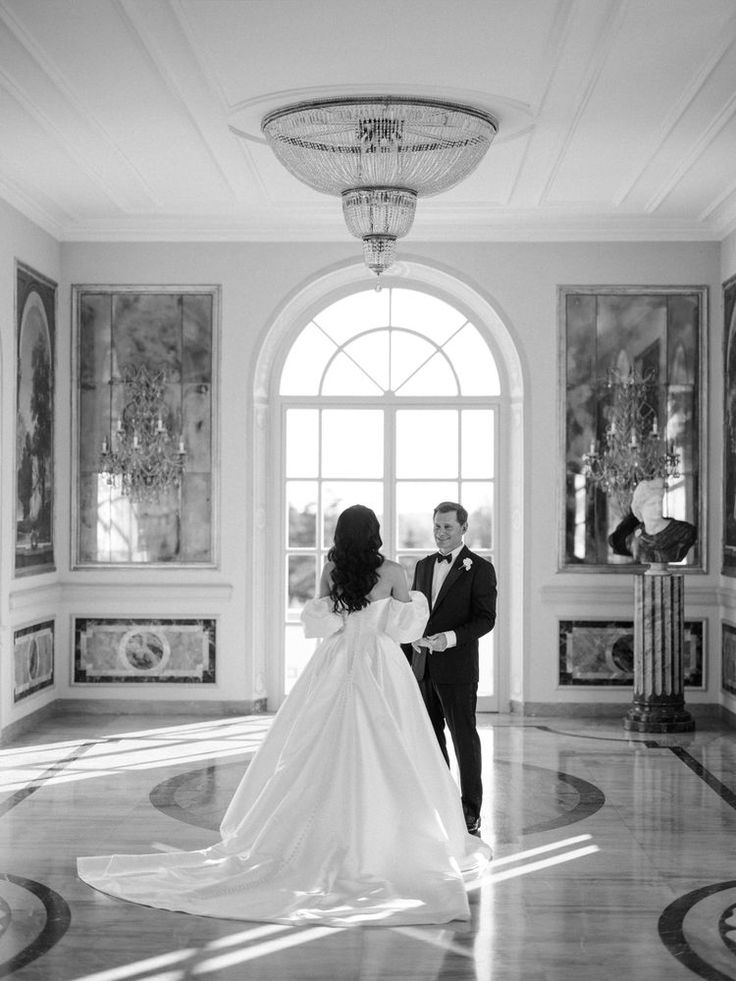 a bride and groom standing in the middle of a room with paintings on the walls