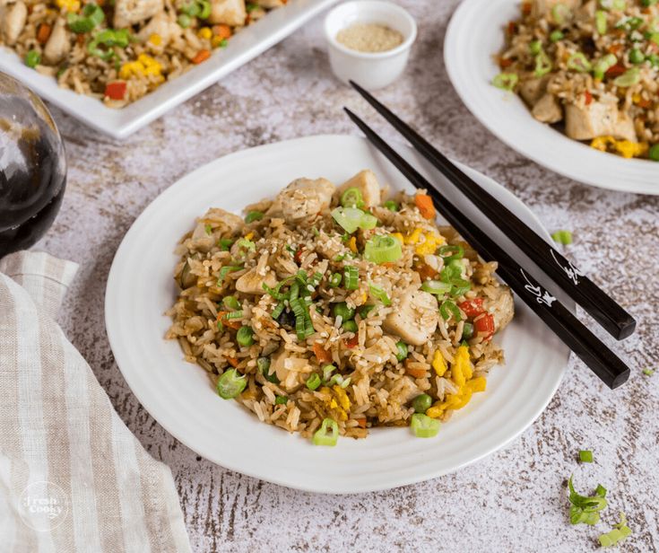 two plates with rice and vegetables on them next to chopsticks