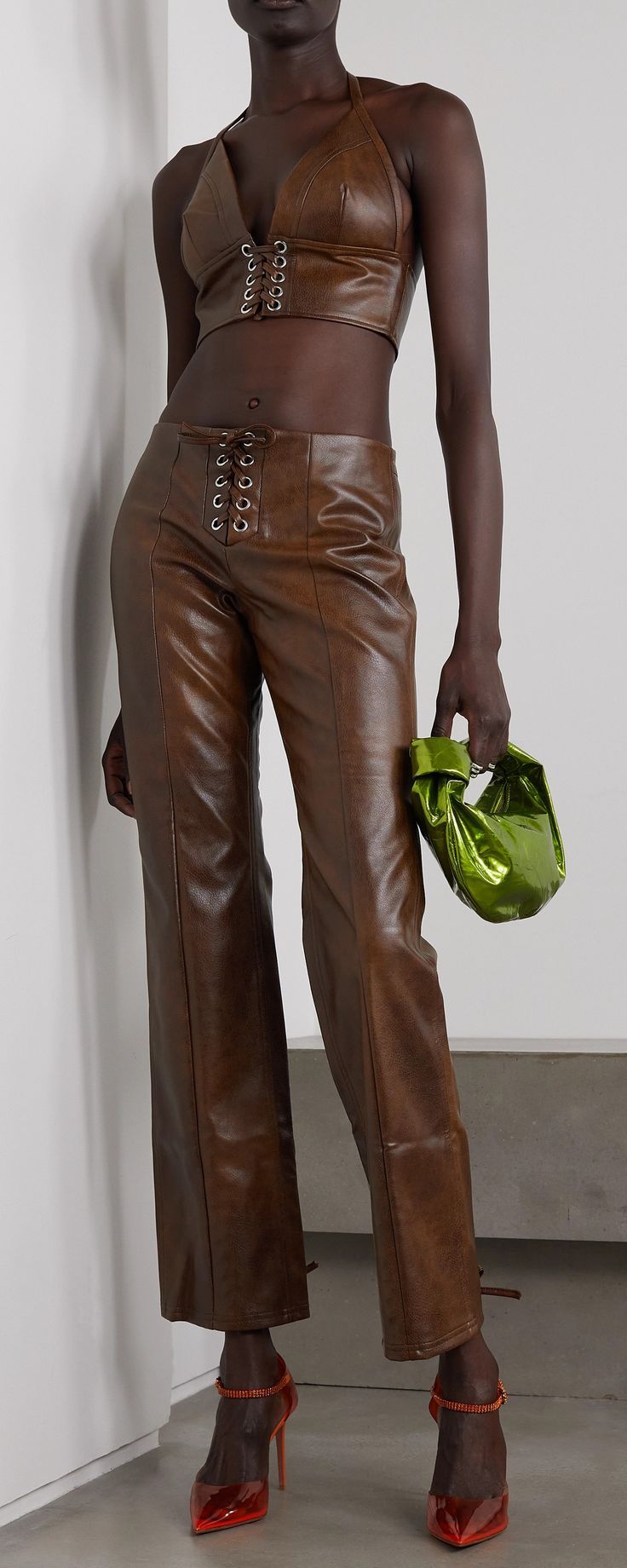 a woman in brown leather is holding a green purse