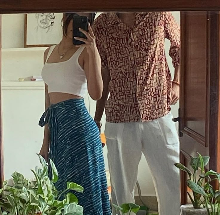 a man and woman standing in front of a mirror taking a selfie with a cell phone