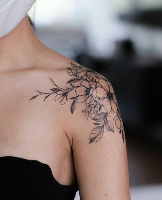 a woman's shoulder with flowers and leaves on it