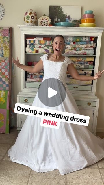 a woman in a white wedding dress standing next to a dresser with her arms out