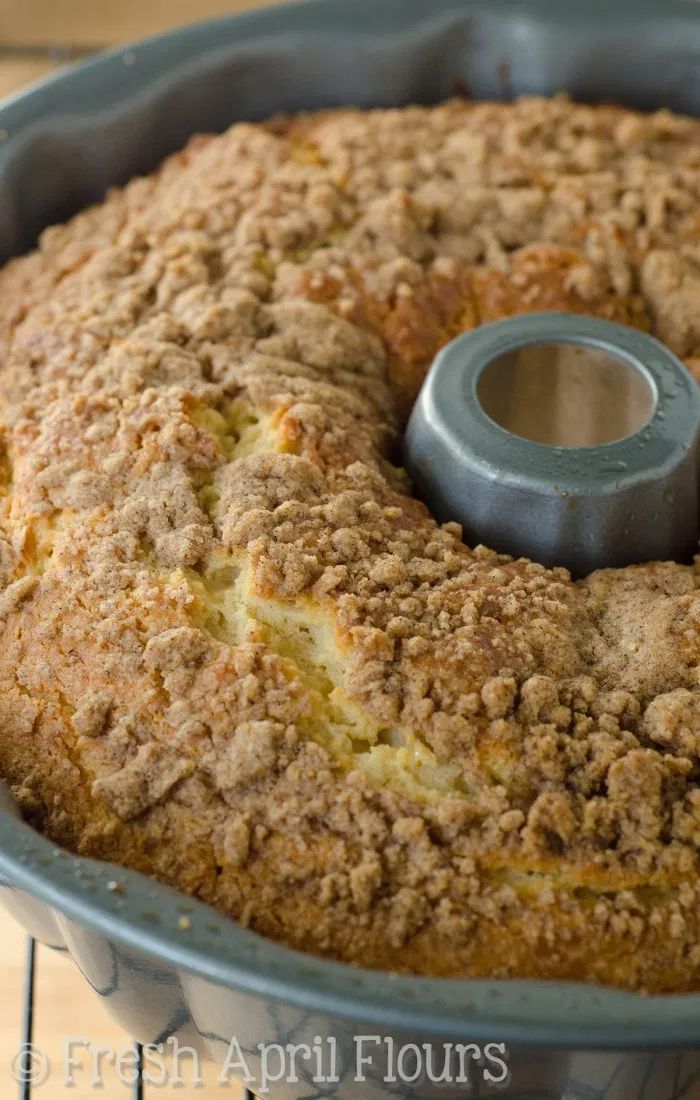 a freshly baked cake in a blue pan on a cooling rack with a metal ring